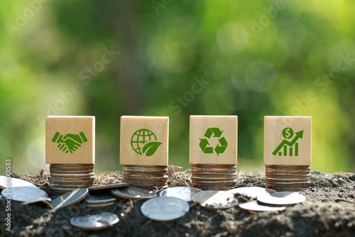 Green icons on wooden cubes on money coin stack. Green business