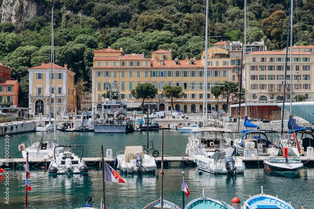 Obraz premium Nice, France - 01 June 2023: View of the port of Nice, moored yachts and boats, and the brightly colored facades of the surrounding houses