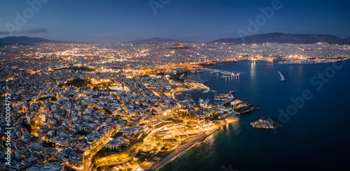 Aerial night view over the illuminated skyline of Piraeus, Athens, Greece, with Kstella Hill, Mikrolimano marina until the Faliro district