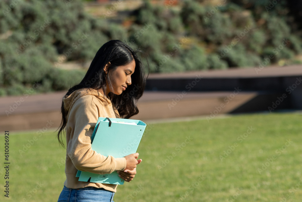 young girl with a blue folder, walking and studying on the campus of the university, hight school or institute.