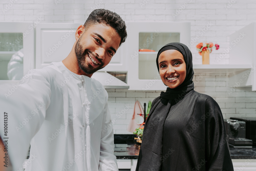Obraz premium happy middle-eastern married couple spending time together at home and wearing traditional arab clothis, Dubai