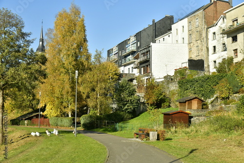 Parc verdoyant en automne entre les façade arrières des immeubles anciens à appartements et le lac des Doyards à Vielsalm photo