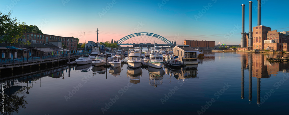 Providence River at sunset with arching highway bridge, moored boats, and three stack chimneys in Rhode Island