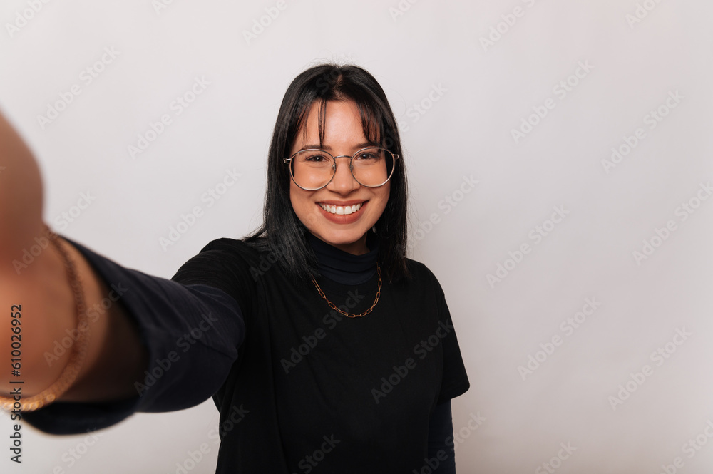 Handsome woman is taking a selfie while smiling over white background.