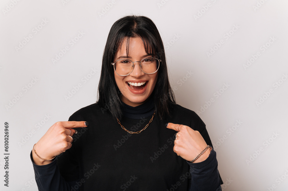 Ecstatic amazed young woman points at herself questioning if it its her.
