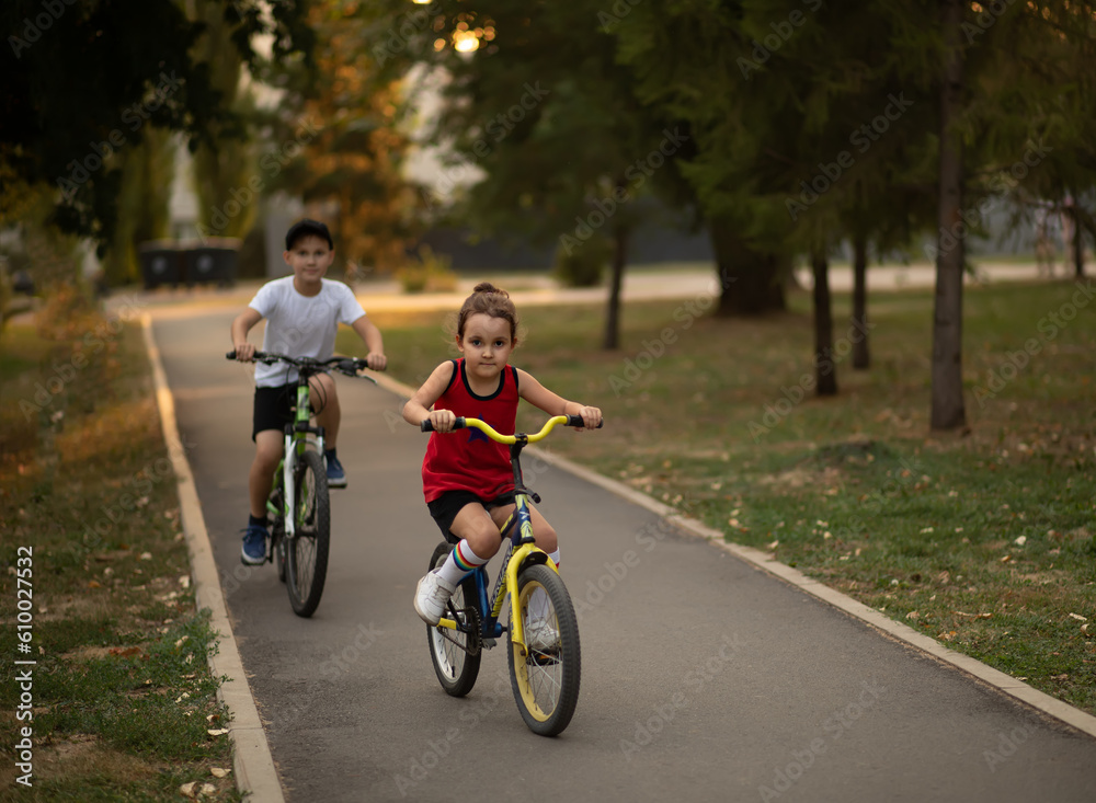 Two little boy and girl cyclists riding their bikes and enjoy having fun. Kid outdoors sport summer activity. Two little boy and girl cyclists riding their bikes and enjoy having fun. Kid outdoors sport summer activity.