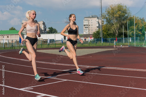 Two athlete young woman runnner on the start at the stadium outdoors © olinchuk