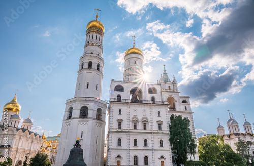 Ivan the Great Bell Tower, with Assumption Belfry on the right in Moscow Kremlin. Blue sky background with sunbeams