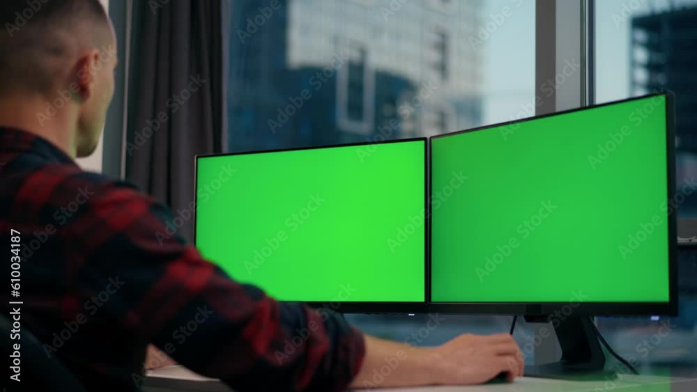 Man Uses Desktop Computer With Two Green Screen Mock Ups Working at Office Man Uses Desktop Computer With Two Green Screen Mock Ups Working at Office