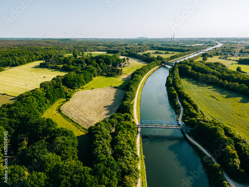 Summer aerial drone view landscape navigable river with bridges, agricultural fields and forests and farmers houses in Germany countryside. 