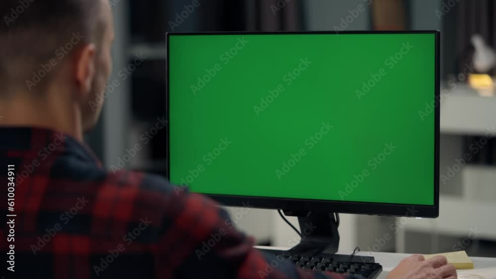 Young Man Working At Computer With Green Mock Up Screen in Home. Close Up Desktop Computer Monitor with Mock Up Green Screen Chroma Key Display Young Man Working At Computer With Green Mock Up Screen in Home. Close Up Desktop Computer Monitor with Mock Up Green Screen Chroma Key Display