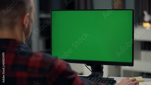 Young Man Working At Computer With Green Mock Up Screen in Home. Close Up Desktop Computer Monitor with Mock Up Green Screen Chroma Key Display