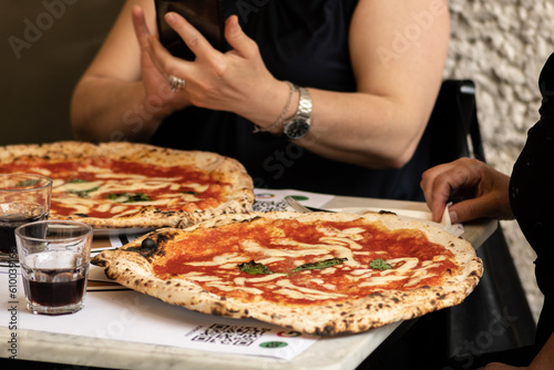Friends eating hot pizza Margherita with tomato sauce, mozzarella and basil in a pizzeria or restaurant in Italy