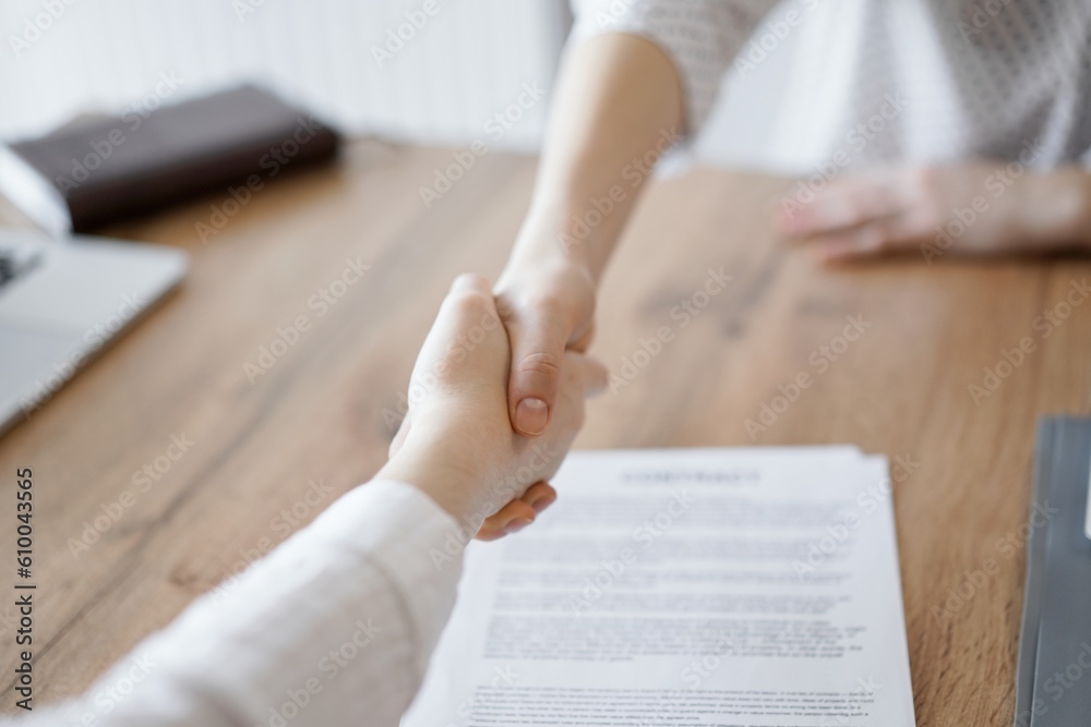Business people shaking hands above contract papers just signed on the wooden table, close up. Lawyers at meeting. Teamwork, partnership, success concept. Business people shaking hands above contract papers just signed on the wooden table, close up. Lawyers at meeting. Teamwork, partnership, success concept.