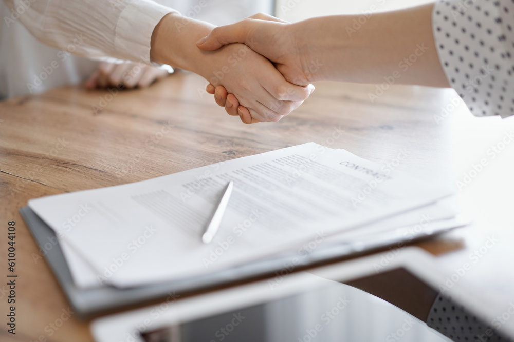 Business people shaking hands above contract papers just signed on the wooden table, close up. Lawyers at meeting. Teamwork, partnership, success concept. Business people shaking hands above contract papers just signed on the wooden table, close up. Lawyers at meeting. Teamwork, partnership, success concept.
