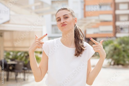 pretty woman with a bad attitude looking proud and aggressive  pointing upwards or making fun sign with hands