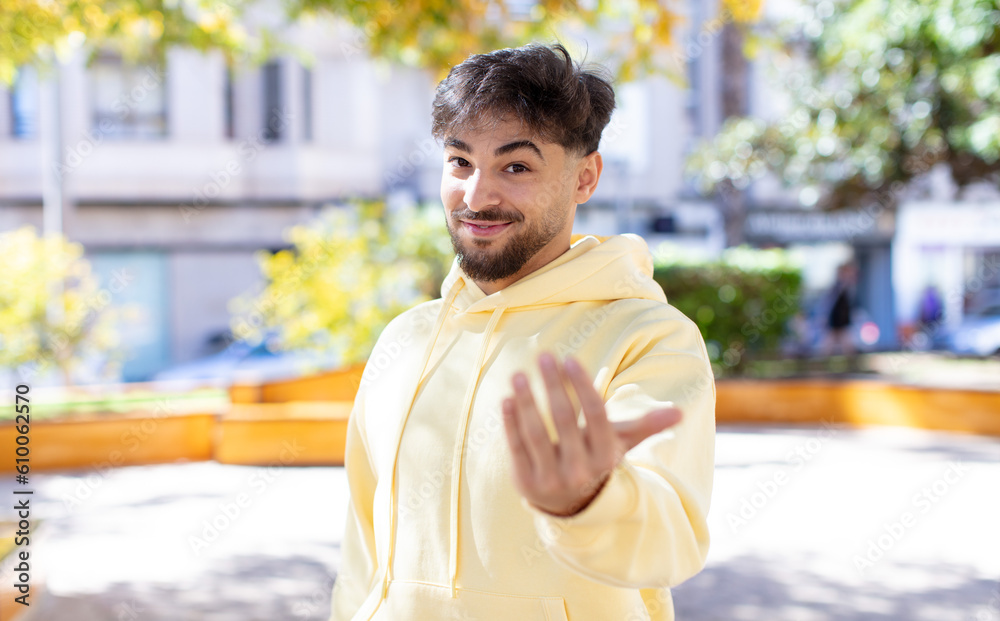 Fototapeta premium young handsome man feeling happy, successful and confident, facing a challenge and saying bring it on! or welcoming you
