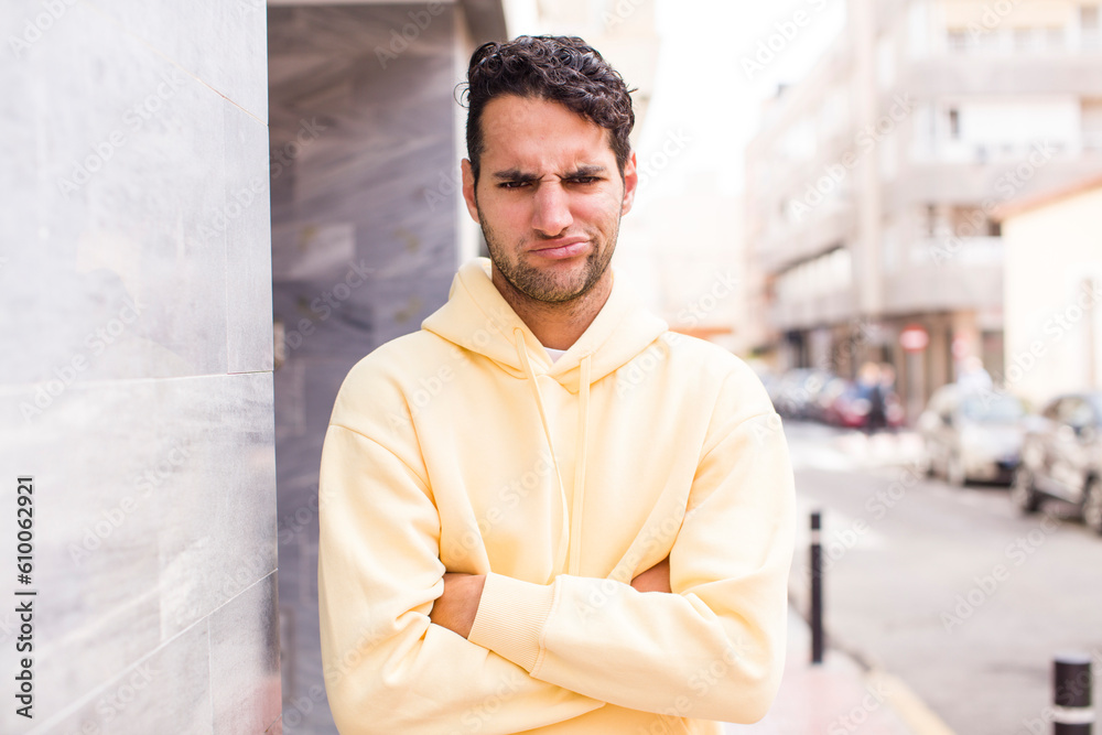Obraz premium young hispanic man feeling displeased and disappointed, looking serious, annoyed and angry with crossed arms