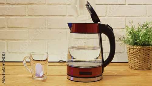 man pours clean filtered water into an electric kettle photo