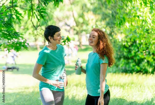 Happy Women Resting and drinking water After Exercising In Park. Fitness, sport and exercise concept