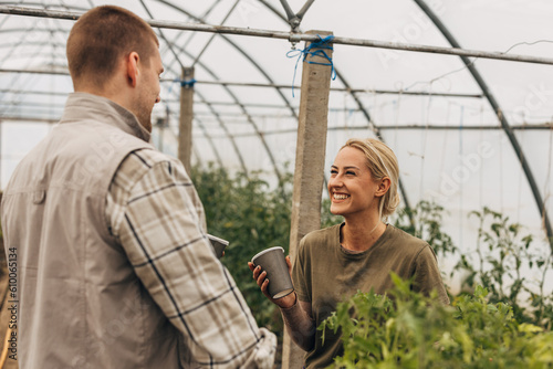 A pretty woman talks to a man in the greenhouse.