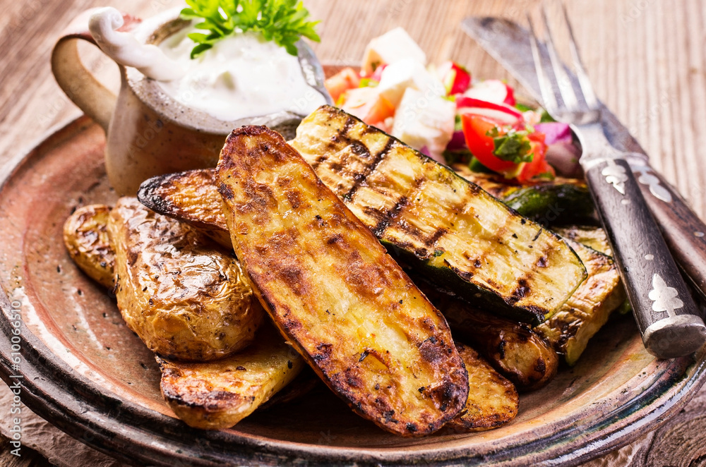 Traditional grilled vegetable with barbecue potatoes an tzatziki served as close-up on a rustic design plate Traditional grilled vegetable with barbecue potatoes an tzatziki served as close-up on a rustic design plate