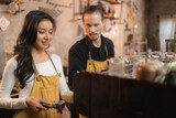 Opening a small entrepreneur business, Happy young Asian woman barista in an apron near a coffee shop bar counter, Small business owner of restaurant or cafe , SME business and shop seller concept