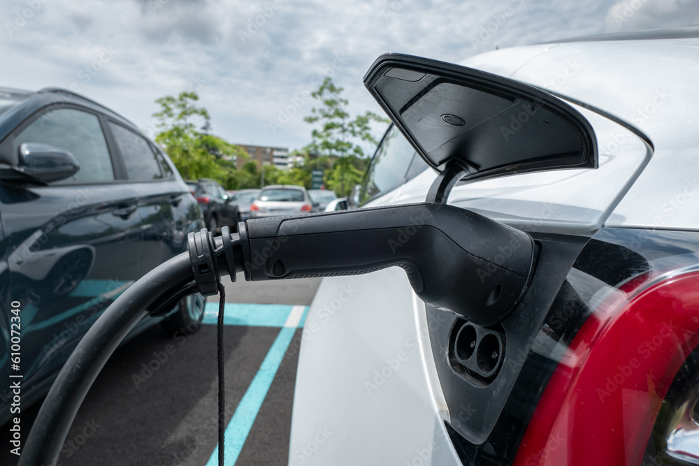 Abastecimento de um carro elétrico com a fonte de alimentação conectada à viatura num posto de serviço para carros elétricos Abastecimento de um carro elétrico com a fonte de alimentação conectada à viatura num posto de serviço para carros elétricos