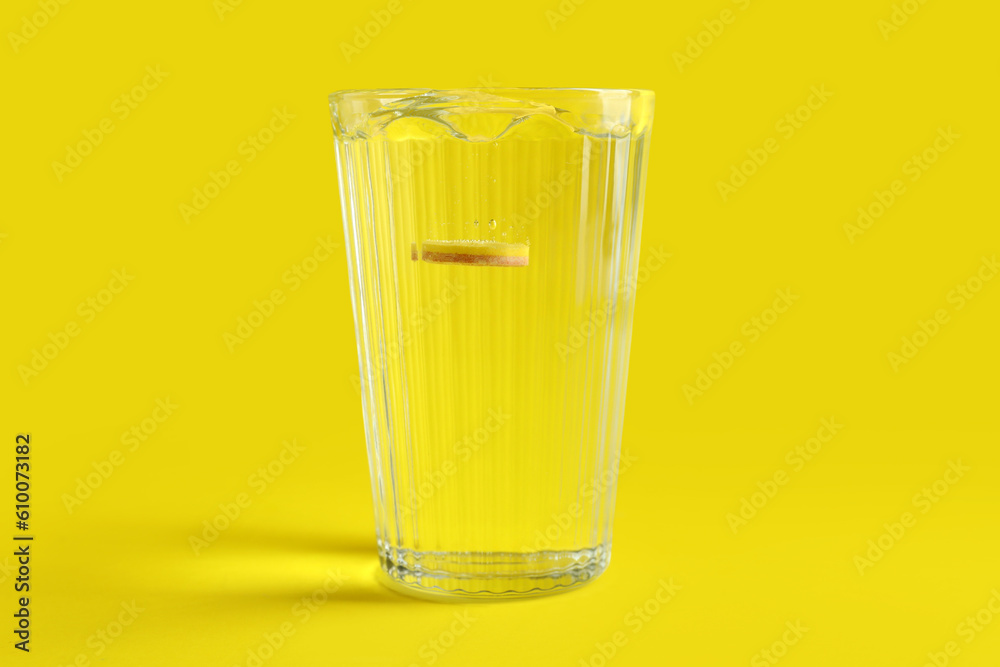 Glass of water with soluble tablet on yellow background Glass of water with soluble tablet on yellow background