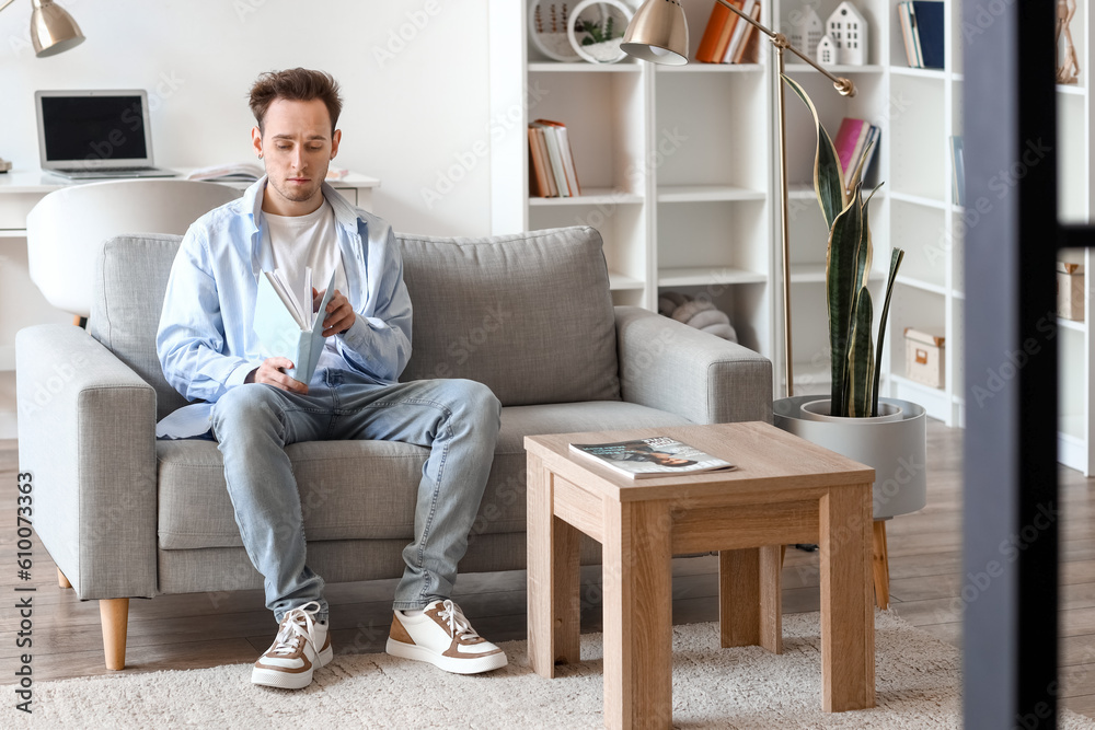 Young man reading book on sofa at home Young man reading book on sofa at home