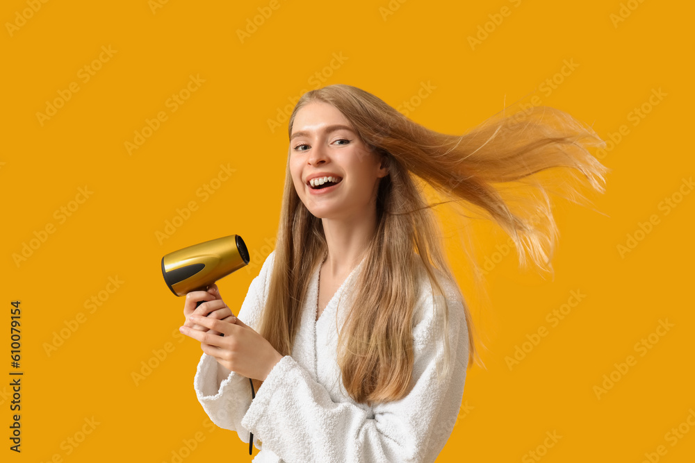 Young blonde woman with hair dryer on yellow background Young blonde woman with hair dryer on yellow background