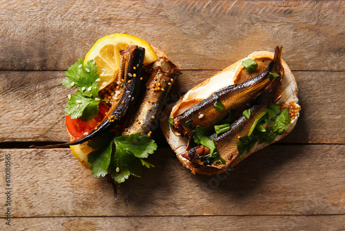 Quadro su tela Tasty sandwiches with canned smoked sprats on wooden background