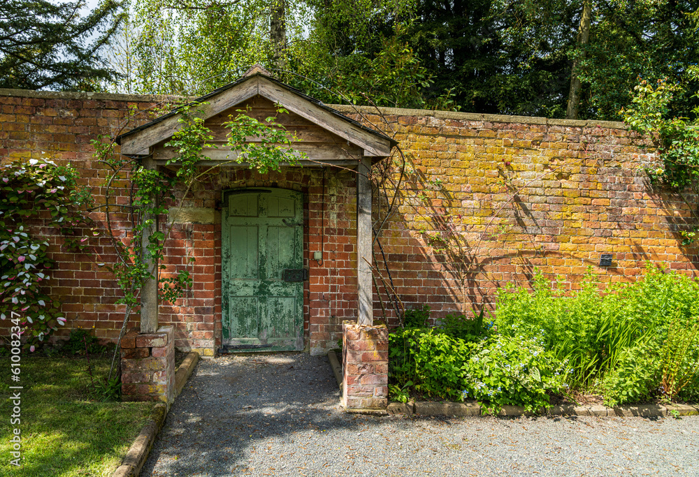 Painted green door and wooden porch as entrance to walled garden made with brick Painted green door and wooden porch as entrance to walled garden made with brick