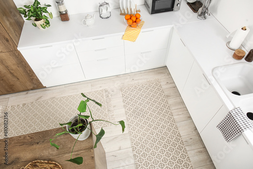 Fotografie Stylish rugs on floor in light kitchen