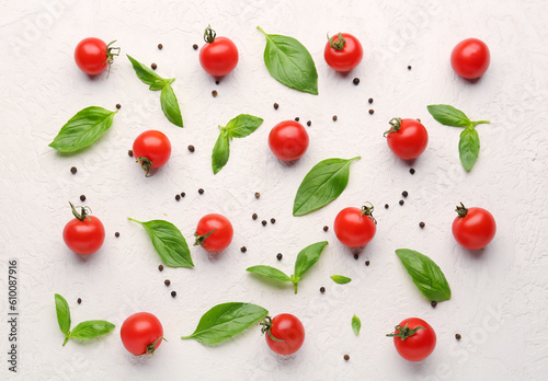 Composition with ripe cherry tomatoes, basil leaves and peppercorn on light background
