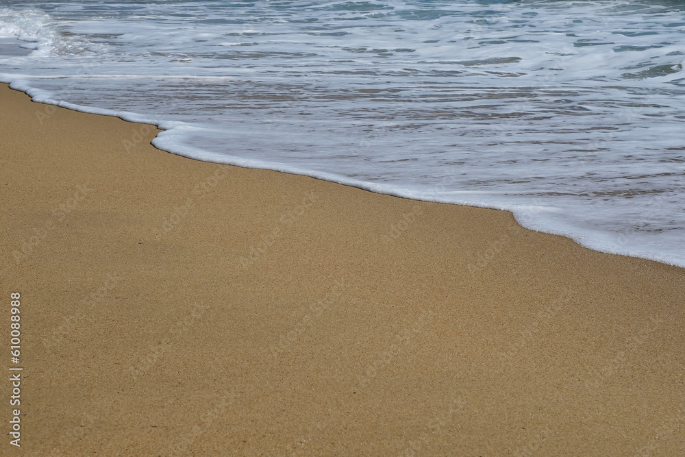 Close up of a beautiful sandy beach and white foamy waves in Ios Greece