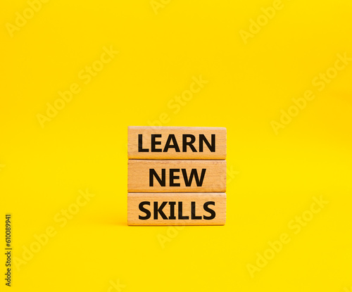 Learn new skills symbol. Concept words Learn new skills on wooden blocks. Beautiful yellow background. Business and Learn new skills concept. Copy space.