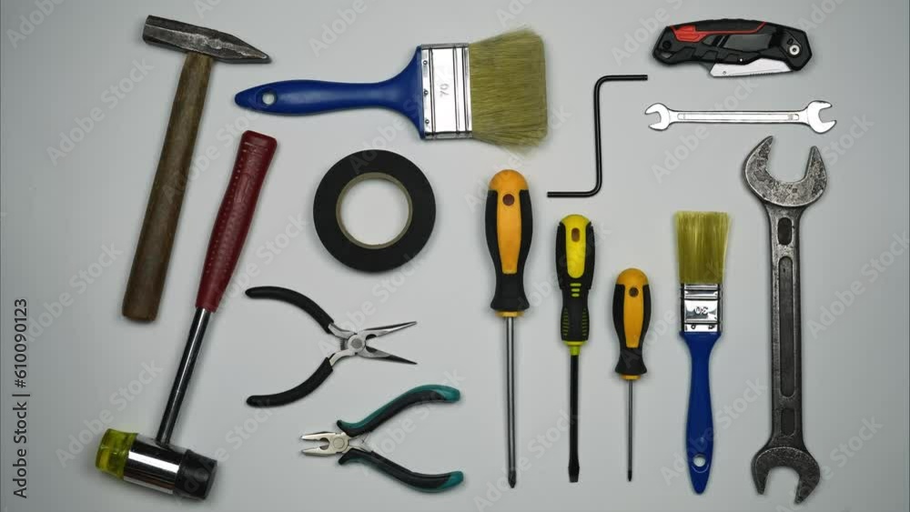Tools for Building Repair On A White Background. A Man's Hand Rakes Everything Freeing The Background For The Inscription Tools for Building Repair On A White Background. A Man's Hand Rakes Everything Freeing The Background For The Inscription