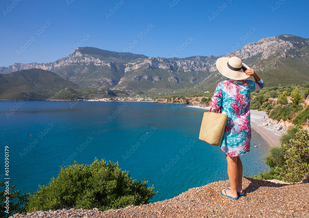 Young woman enjoys the beautiful view of the Agia Kyriaki beach, Kiparissi Lakonia village, Zorakas Bay, Greece.