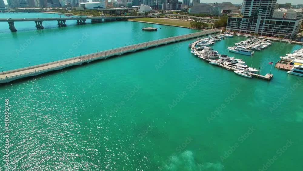 Aerial Tilt Up Shot Of Boats Moored At Harbor Near Buildings And Bridges, Drone Flying Over Sea Near Modern City Against Sky On Sunny Day - Miami, Florida Aerial Tilt Up Shot Of Boats Moored At Harbor Near Buildings And Bridges, Drone Flying Over Sea Near Modern City Against Sky On Sunny Day - Miami, Florida