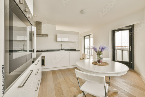 a kitchen and dining area in a modern apartment with white cabinets  wood flooring and an oven on the wall