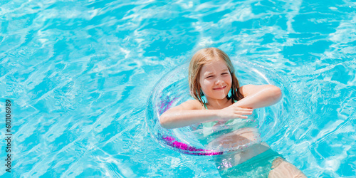 Cute funny teen girl in a swimsuit with an inflatable lifebuoy swims in the pool