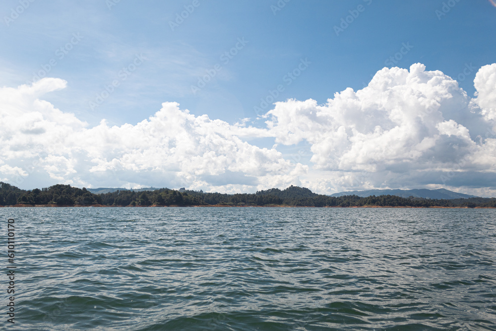 A landscape seen from a dam. Water with small waves and mountains in the background on a sunny day. Guatape, Antioquia in Colombia.