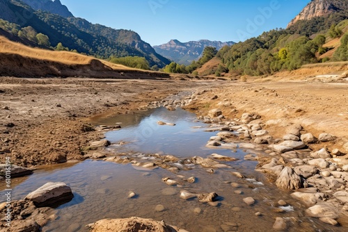 nearly dry riverbed in the mountains due to drought and rain shortage on a sunny day - concept of drought and climate change - generative AI