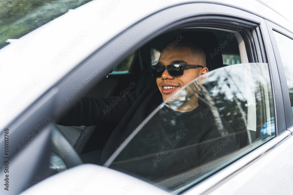 Handsome young black man driving car with glass window half open side profile view. High quality photo