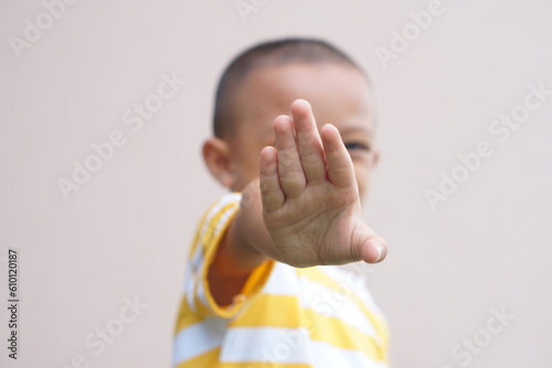 The boy raised his hand in front of himself to defend himself.