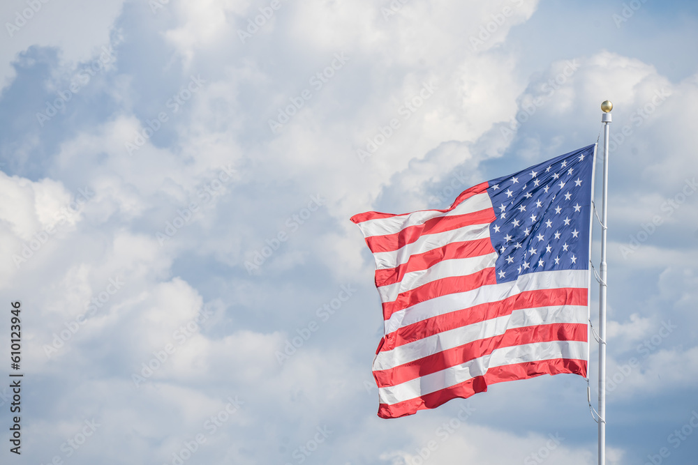 Obraz premium American Flag flying against blue skies and clouds