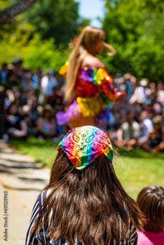 A young person wearing a rainbow kerchief watches a performance at a gay pride event. photo