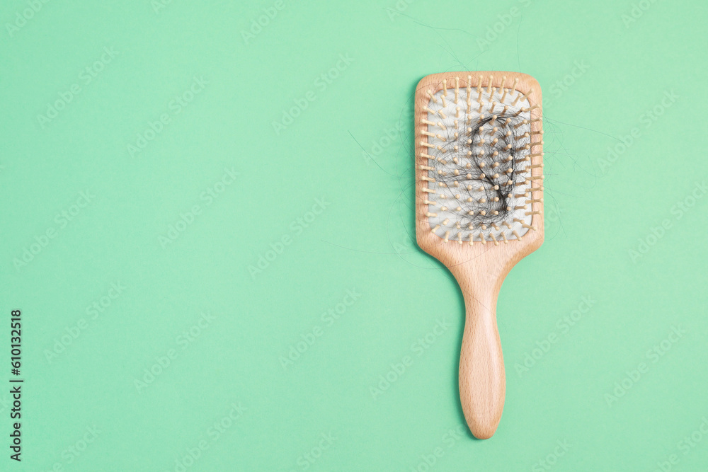 Wooden brush with lost hair on green background, top view. Space for text Wooden brush with lost hair on green background, top view. Space for text