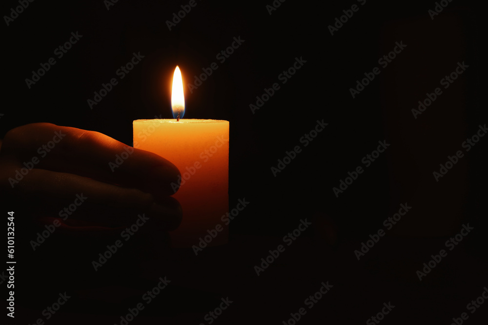 Woman holding burning candle in hand on black background, closeup. Space for text Woman holding burning candle in hand on black background, closeup. Space for text